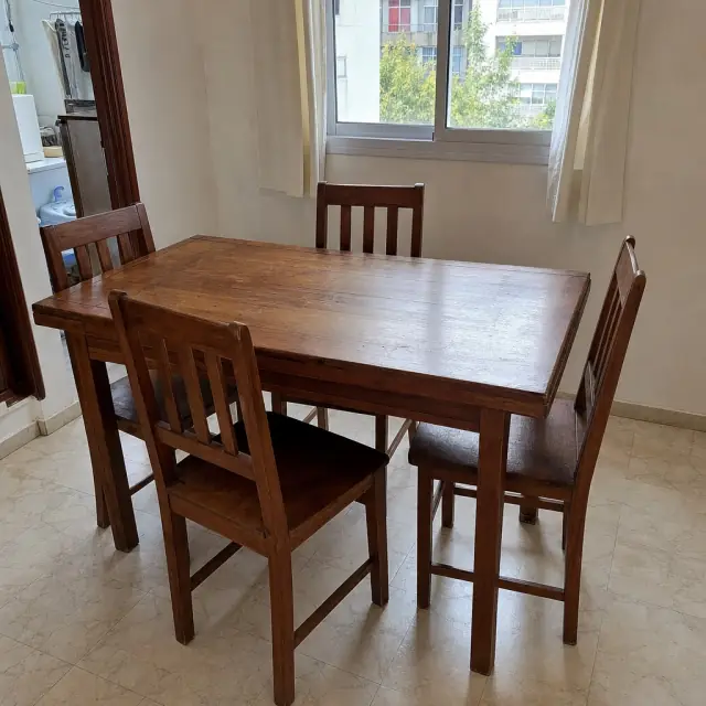 Wooden dining table with four chairs by a window