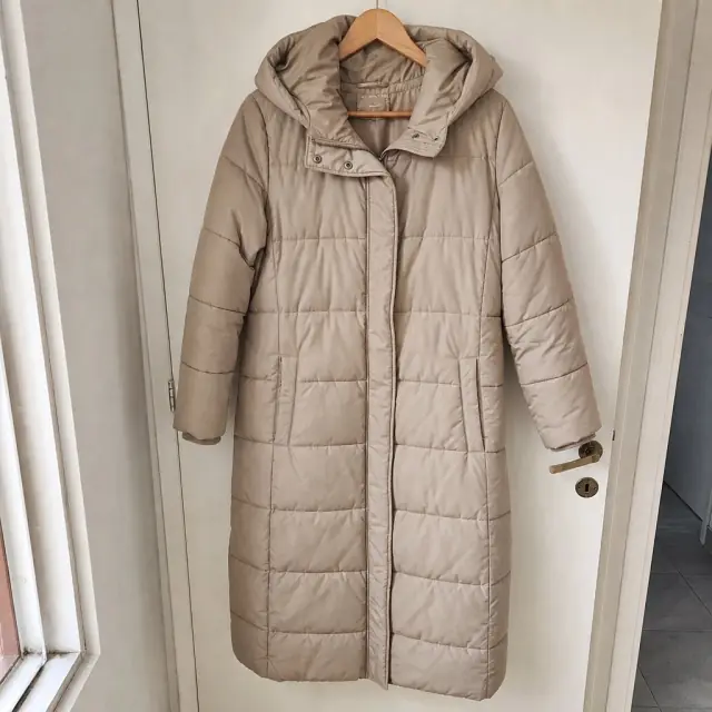 Campera larga beige en una percha