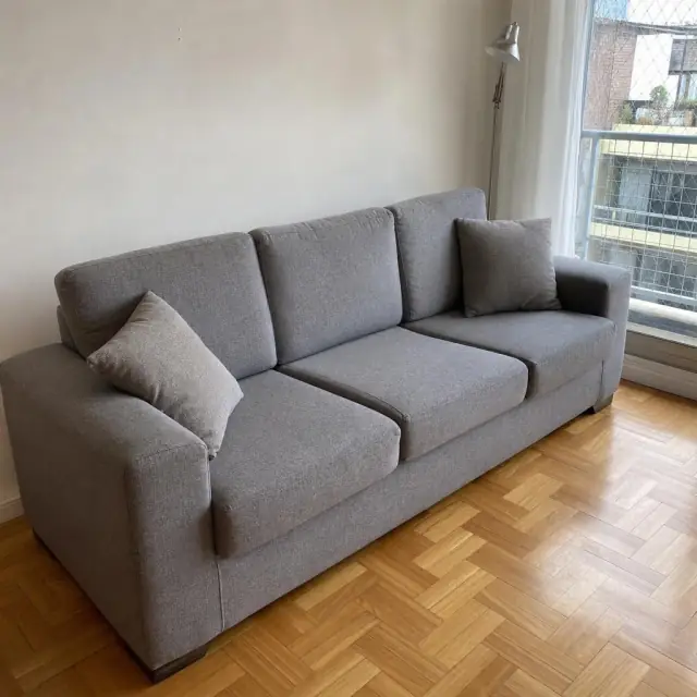 Sillón gris de tres cuerpos en un living